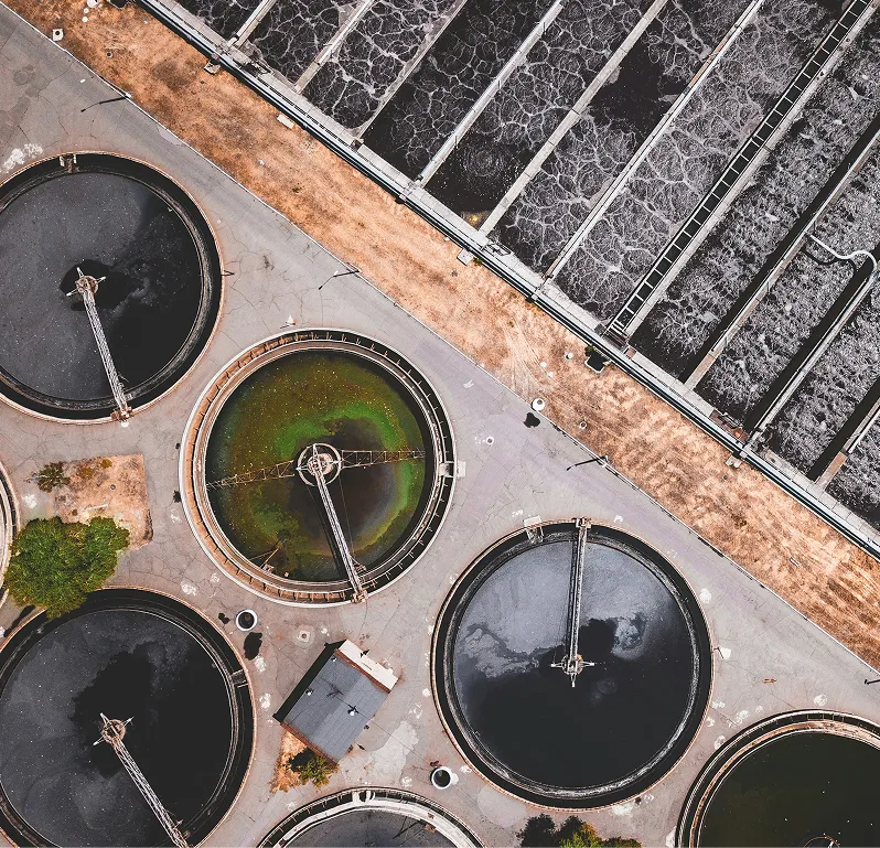 Direct overhead view of large circular and rectangular industrial wastewater treatment basins.