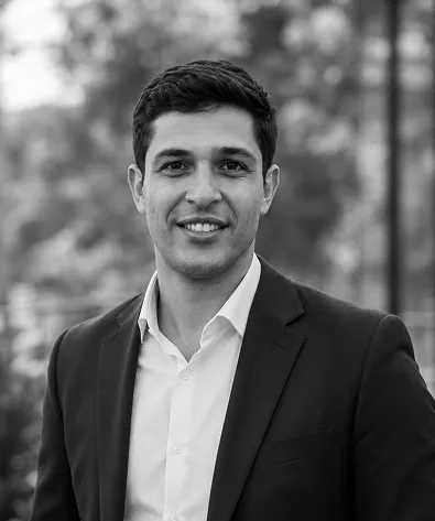 Black and white headshot of a smiling man in a suit jacket and white shirt.